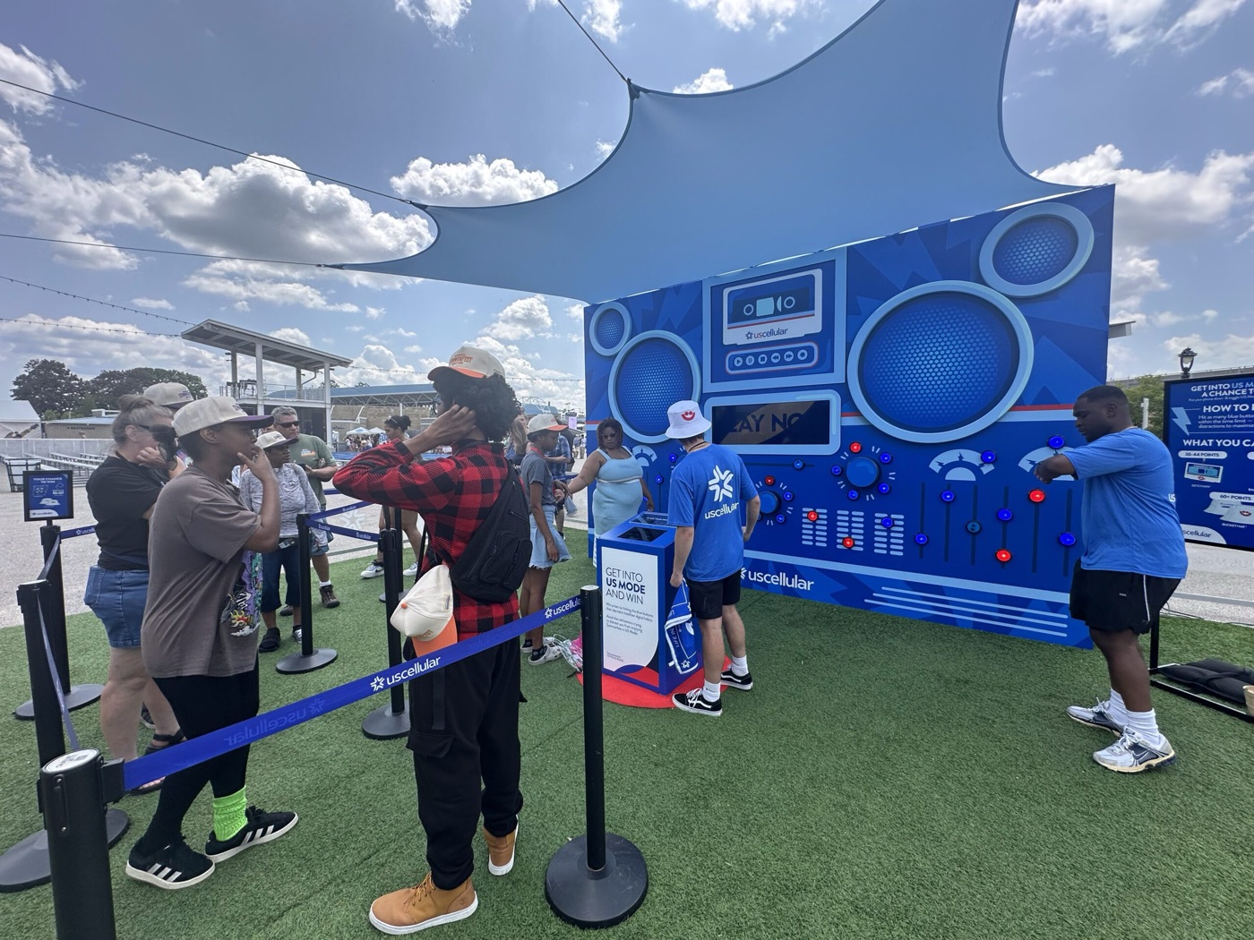 A queue of festivalgoers waiting behind branded stanchions as players hit the wall